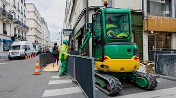 Construction workers in safety vests operate heavy machinery at an urban roadwork site, depicting infrastructure development and labor photo