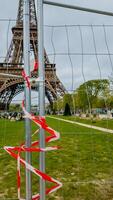 un barrera con rojo y blanco cinta en frente de el eiffel torre en París, simbolizando restringido acceso, fotografiado en abril 14, 2024, durante primavera foto