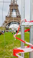 Red and white caution tape at a security barrier with the Eiffel Tower in the background, symbolizing public safety, shot in Paris, France on April 14th, 2024 photo