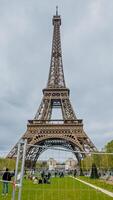 Tourists enjoying a spring day near the iconic Eiffel Tower in Paris, France, with clear skies on April 14th, 2024, ideal for travel and holiday themes photo