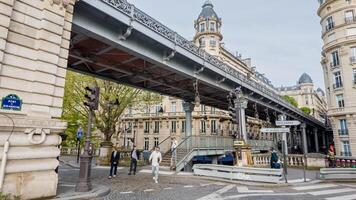 Citizens stroll under the iconic metal viaduct in Paris, France, capturing the essence of urban European life on a cloudy spring day, April 14th, 2024 photo