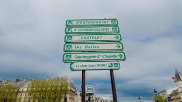 Directional signpost featuring iconic Parisian destinations against a cloudy sky, shot in Paris, France on April 14, 2024, ideal for travel and tourism themes photo