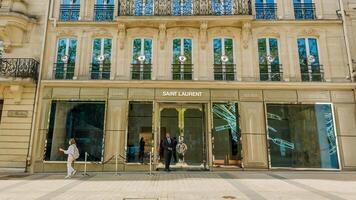 Elegant storefront of Saint Laurent boutique with people passing by on a sunny spring day in Paris, France, related to fashion and luxury retail, April 14, 2024 photo