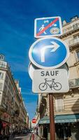 Vertical European traffic signs indicating a no entry except for bicycles and compulsory right turn against a clear blue sky, Paris, France, April 14th, 2024 photo