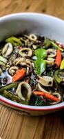 ndonesian home cooking menu, sauteed squid with black ink sauce with spicy seasoning called Tumis Cumi Hitam, including chili, ginger, and lime leaf photo