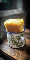 Ice chocolate drink on a vintage Indonesian iron mug with random green pattern called Blirik cup or cangkir Blirik on bokeh background along with chocolate filling bread photo