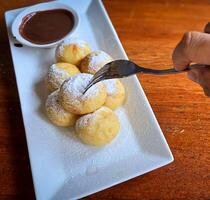 Homemade Dutch poffertjes mini pancakes with icing powdered sugar and chocolate fillings with additional chocolate sauce photo