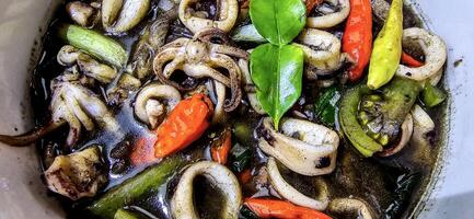 ndonesian home cooking menu, sauteed squid with black ink sauce with spicy seasoning called Tumis Cumi Hitam, including chili, ginger, and lime leaf photo