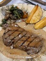 Sirloin steak grilled medium rare served with potatoes and salad with mushroom black pepper sauce in a restaurant photo