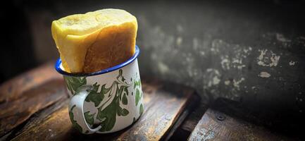 Ice chocolate drink on a vintage Indonesian iron mug with random green pattern called Blirik cup or cangkir Blirik on bokeh background along with chocolate filling bread photo