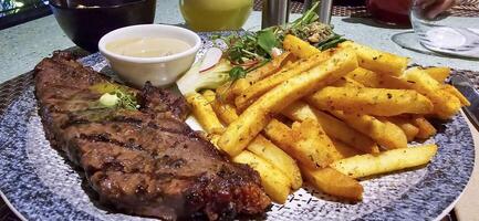 Beef New York strip loin steak or sirloin steak served with potatoes, and mushroom sauce and salad on plate photo