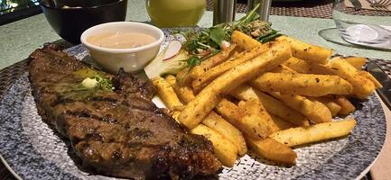 Beef New York strip loin steak or sirloin steak served with potatoes, and mushroom sauce and salad on plate photo