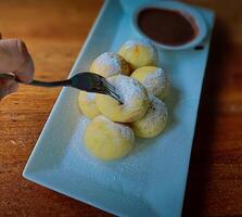 Homemade Dutch poffertjes mini pancakes with icing powdered sugar and chocolate fillings with additional chocolate sauce photo