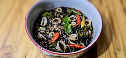 ndonesio hogar Cocinando menú, salteado calamar con negro tinta salsa con picante Condimento llamado tumis cumi hitam, incluso chile, jengibre, y Lima hoja foto