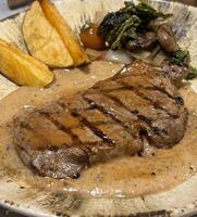 Sirloin steak grilled medium rare served with potatoes and salad with mushroom black pepper sauce in a restaurant photo