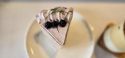 slice of blueberry cake decorated with fresh berries on white plate, delicious layered cake, top view photo