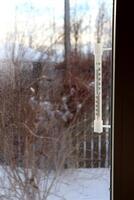 A plastic retro thermometer outside the window of a village house photo