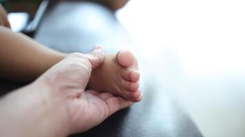 Close-up of a father's hand holding his son's foot. Slow motion video