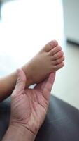 Close-up of a father's hand holding his son's foot. Slow motion video