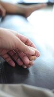 Close-up of a father's hand holding his son's foot. Slow motion video