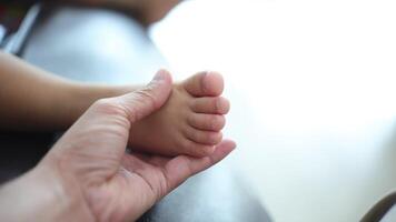 Close-up of a father's hand holding his son's foot. Slow motion video