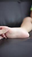 Close-up of a father's hand holding his son's foot. Slow motion video