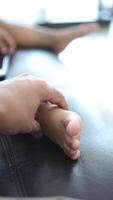 Close-up of a father's hand holding his son's foot. Slow motion video