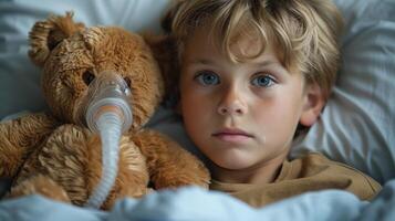 joven chico con cístico fibrosis en hospital cama con osito de peluche oso y respiración máscara foto