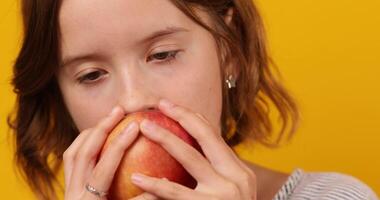 bonito adolescente chica, niño comer, picaduras un Fresco rojo manzana aislado video