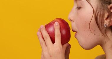 bonito adolescente chica, niño comer, picaduras un Fresco rojo manzana aislado video