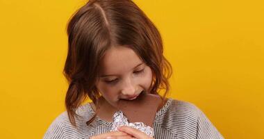 bonita adolescente menina comer, mordidas uma chocolate Barra isolado video