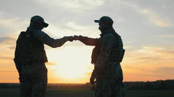 Schöne Grüße von das Soldaten von das ukrainisch Armee. Krieg im Ukraine. zwei Soldaten Gruß jeder andere beim Sonnenuntergang. video