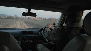 soldato guida su rurale strada a crepuscolo, militare personale guida un' veicolo attraverso rurale terreno a crepuscolo. video