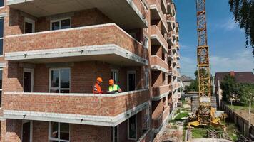 un ingeniero y un arquitecto considerar el plan de construcción y comunicaciones de el casa. casa debajo construcción. video