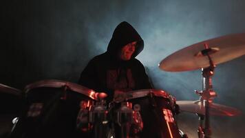 baterista músico tocam bateria em estágio. baterista desempenho. Sombrio quarto e luz de fundo. video