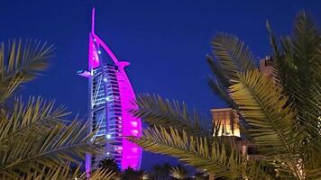 Émirats arabes unis, Dubai - uni arabe émirats 01 avril 2024 burj Al arabe allumé en haut dans violet à nuit, iconique burj Al arabe Hôtel illuminé dans violet éclairage à nuit, encadré par paume des arbres video