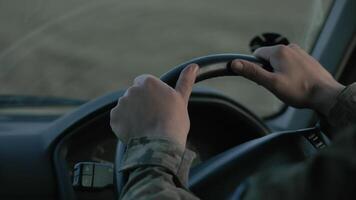 Soldier of the Ukrainian army. Close-up of a soldier's hands on the steering wheel, driving a vehicle at twilight. video