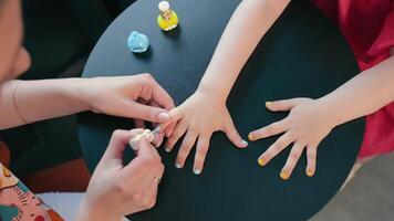 Children's manicure. The master paints the child's nails in blue and yellow video
