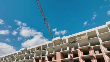 el construcción grua se mueve el auge sin un carga. construcción de un Alto edificio desde un monolito. un multi-apartamento residencial edificio debajo construcción. video