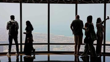 UAE, Dubai - United Arab Emirates 01 April 2024 People Observing City Horizons from Skyscraper in Dubai, Silhouetted figures against the expansive city horizon from a high vantage point in a Dubai video