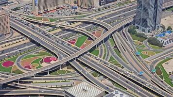 antenne visie van complex snelweg uitwisseling in dubai, ondersteboven visie van een kleurrijk en complex snelweg uitwisseling met weelderig landschapsarchitectuur en meerdere wegen in Dubai video
