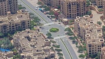 Aerial View of Roundabout in Dubai's Residential Neighborhood. Overhead view of a roundabout surrounded by residential buildings, lush greenery, and palm trees in a serene Dubai neighborhood video