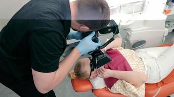un dentista toma un imagen de un del paciente dientes. un médico fotógrafo capturas su trabajo con el ayuda de fotografía. foto reporte en odontología. video
