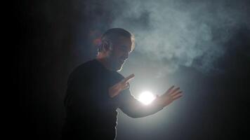 Silhouette von ein Darsteller im ein dunkel Halle. Licht und Rauch im ein dunkel Halle auf Bühne. video