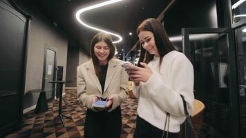 Ukraine Lviv 05.03.2023 Girls with phones are smiling. Girls look for information on mobile phones and smile before the conference video