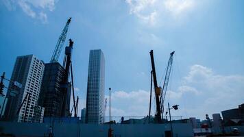 A timelapse of moving cranes at the under construction in Tokyo wide shot panning video