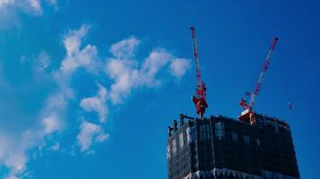 un lapso de tiempo de grúas a el debajo construcción detrás el azul cielo en tokio video