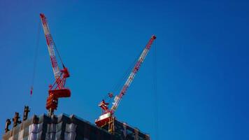 A timelapse of cranes at the under construction behind the blue sky in Tokyo video