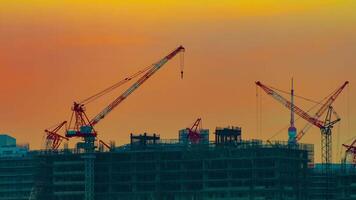 une temps laps de en mouvement grues à le en dessous de construction dans tokyo à crépuscule video