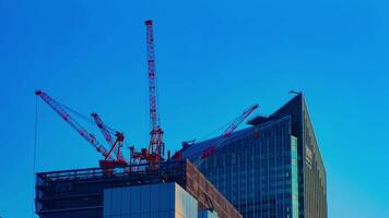 un' lasso di tempo di gru a il sotto costruzione dietro a il blu cielo nel tokyo video